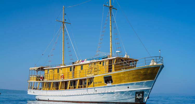 Un gran velero de madera con cielo azul y agua.