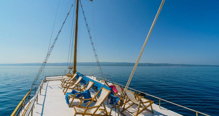 La cubierta de un velero con sillas de descanso con vista al agua.
