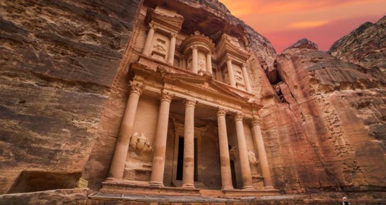 La façade emblématique du Trésor à Petra illuminée par les couleurs chaudes du coucher de soleil contre les falaises escarpées
