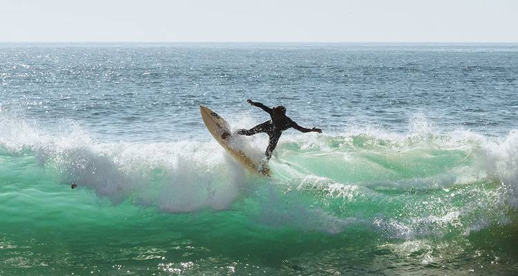 Surfeur attrapant une vague dynamique avec des embruns sous un soleil éclatant