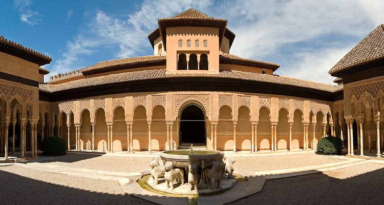 Vue panoramique de la cour intérieure de la Cour des Lions de l'Alhambra avec ses arches ornées et sa fontaine centrale.