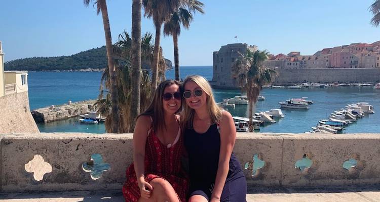 Deux femmes assises avec une vue sur une ville portuaire historique.