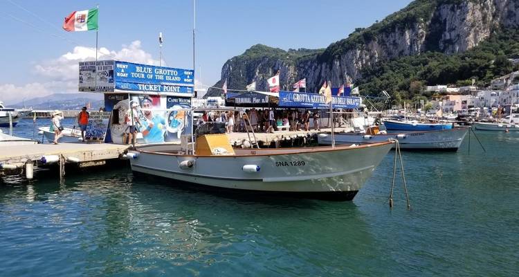 Bateau amarré à une marina avec des panneaux pour la visite de la Grotte Bleue.