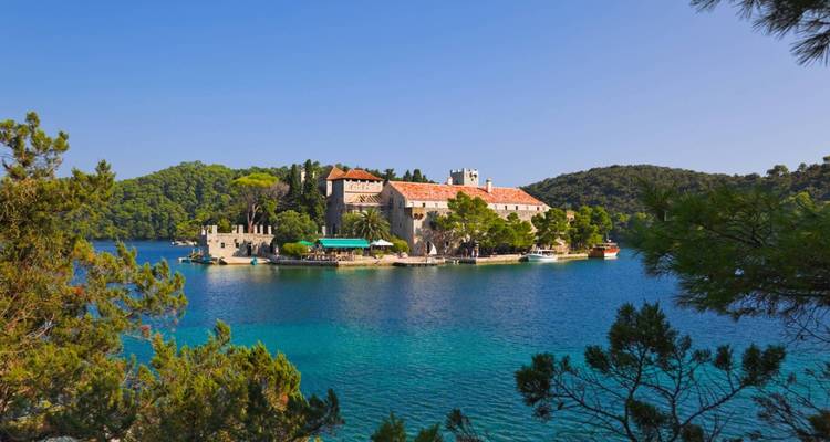 Monastery island surrounded by pine forest and clear water.