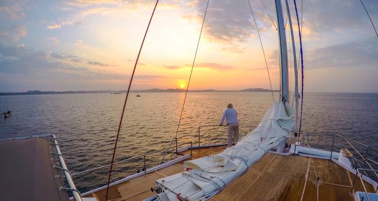 Un pasajero contempla la puesta de sol resplandeciente desde la cubierta de un yate