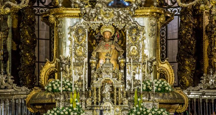 Altar dorado ornamentado que presenta una estatua ricamente detallada de Santiago rodeada de flores y tallas barrocas.