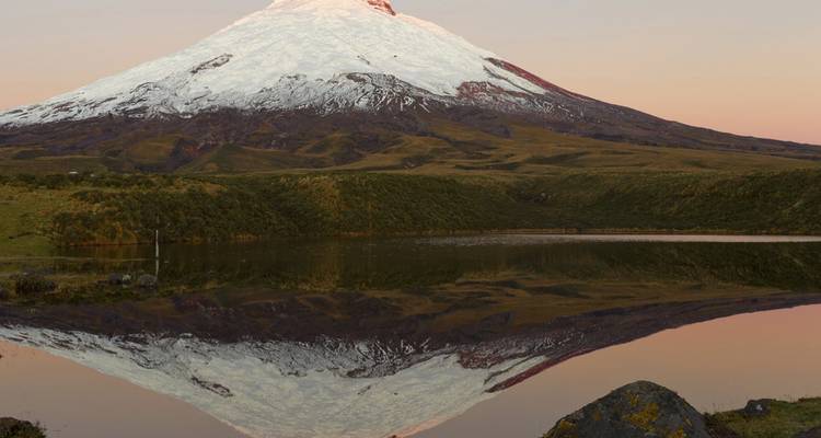 Volcán Cotopaxi cubierto de nieve reflejado perfectamente en una laguna tranquila al amanecer