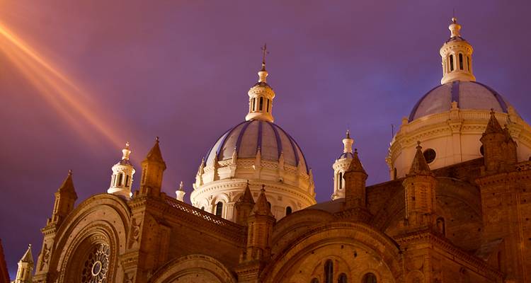 Torres de la catedral de cúpula azul iluminada contra un dramático cielo crepuscular púrpura