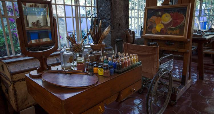 Un coin d'atelier d'artiste avec des pots de peinture, des pinceaux et un chevalet à l'intérieur d'une demeure historique mexicaine.
