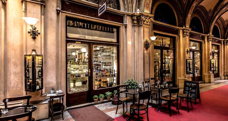 Cafe tables outside a historical indoor market with arched ceilings.