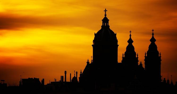 Silhouette of a cathedral against a fiery sunset sky