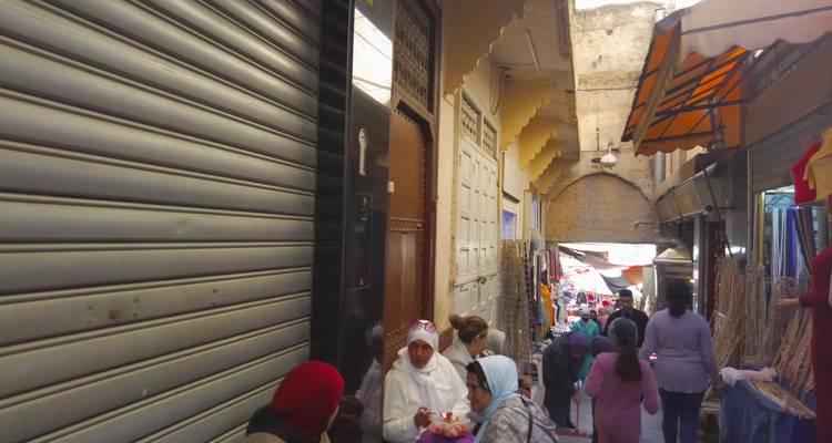 Drukke smalle marktstraat met lokale bewoners en winkelende mensen onder gedeeltelijke luifels