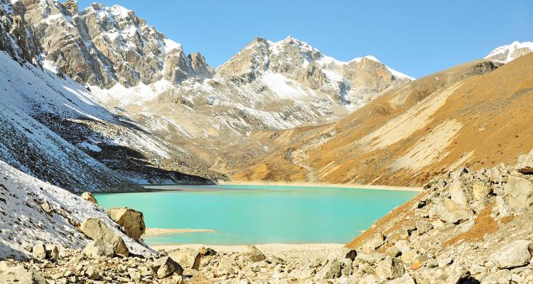 Der türkisfarbene Gokyo-See, eingebettet zwischen schneebedeckten Himalaya-Gipfeln unter einem klaren Himmel.