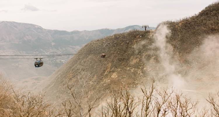 Cable cars moving over a volcanic landscape.