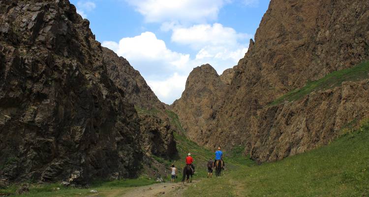 Menschen auf Pferden reiten über einen Bergpass.