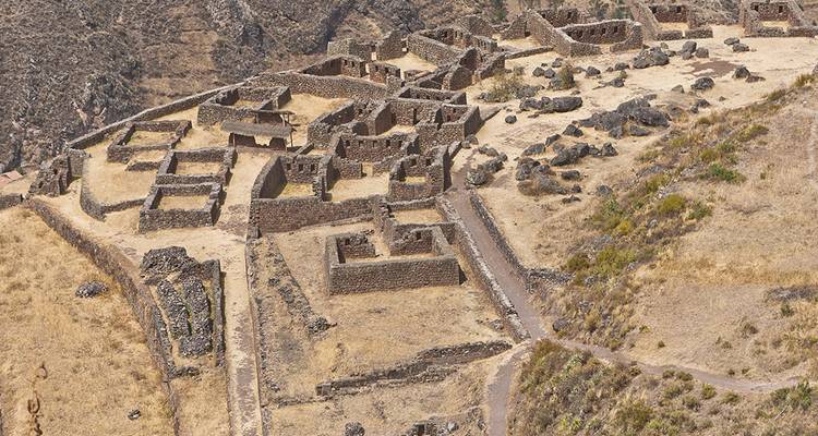Vista aérea de extensas ruinas incas de la estación seca y fundaciones en terrazas esparcidas por una ladera.