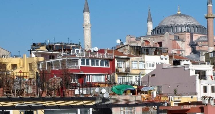 Skyline urbain caractérisé par des minarets et des dômes, y compris la Sainte-Sophie, sous un ciel d'Istanbul dégagé et bleu.