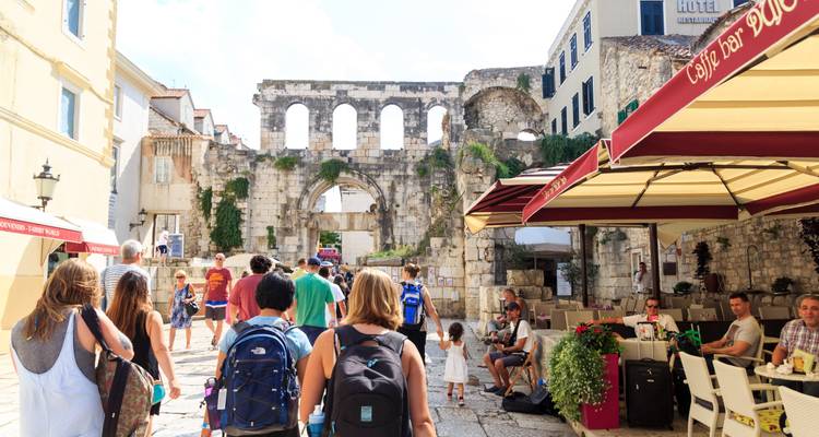 Personas caminando en una parte histórica de la ciudad cerca de ruinas.