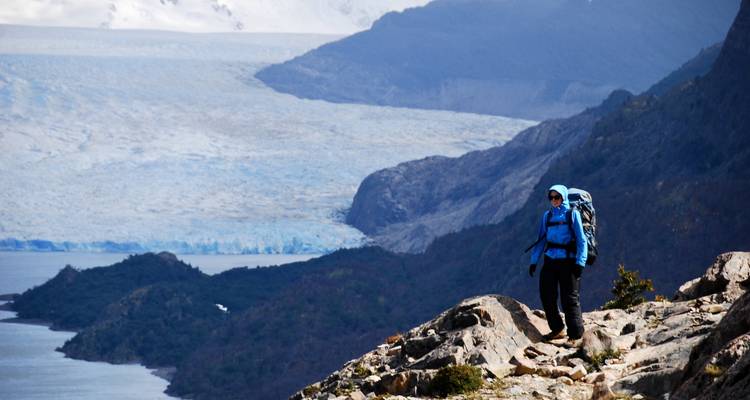 Persona parada en un afloramiento rocoso con un glaciar al fondo