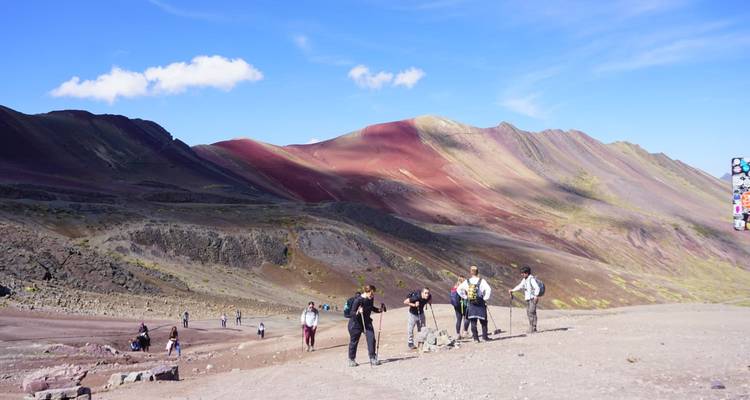 Randonneurs marchant le long de collines vallonnées et colorées dans les montagnes.