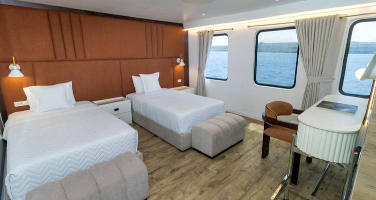 Cabine double moderne sur un petit yacht de croisière avec de grandes fenêtres face à la mer.