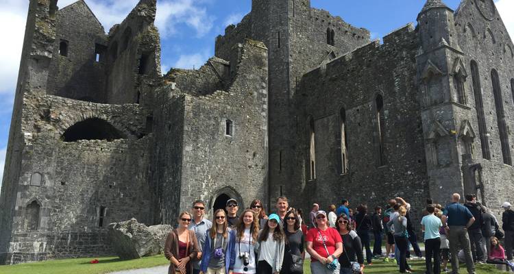 Groupe de touristes devant un bâtiment historique en pierre.