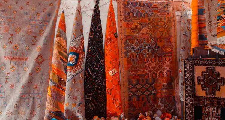 Tapis colorés tissés à la main exposés verticalement sur un mur.
