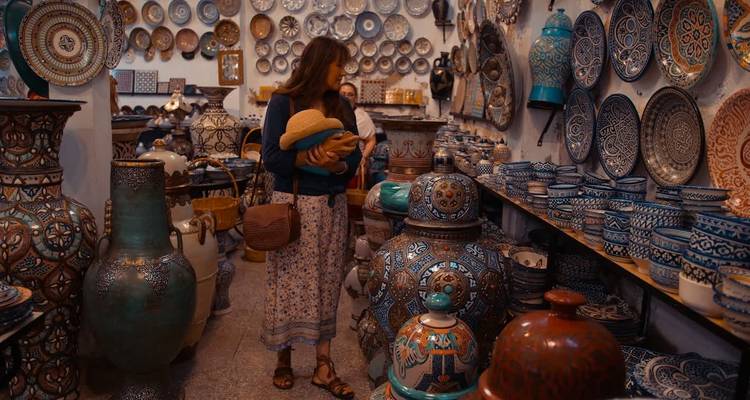 Femme dans une boutique entourée de poterie marocaine colorée.