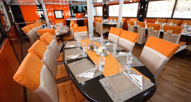Salle à manger avec tables soigneusement disposées sur un navire.