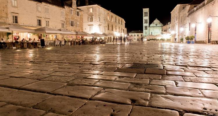 Place pavée la nuit avec des lumières illuminant la zone.