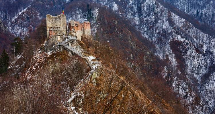 Ruins of a castle on a snowy mountain ridge.