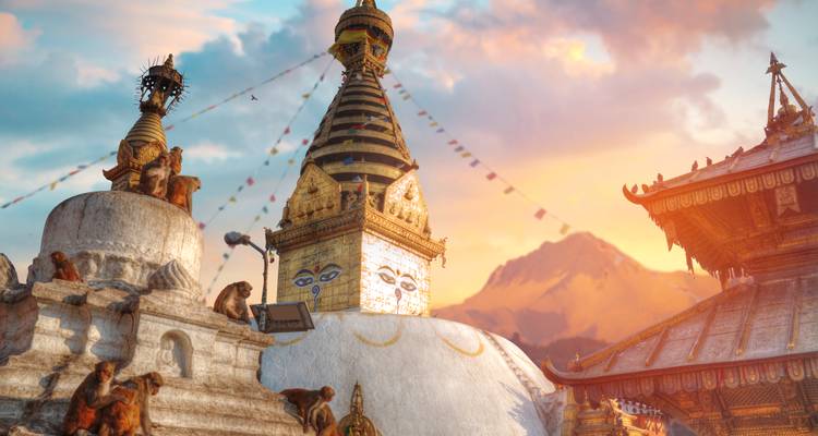 Swayambhunath stupa with playful monkeys at golden sunset, snow-capped mountain peak in the background.