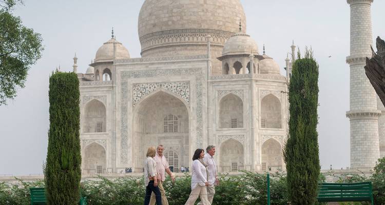 Visitors walk past manicured cypress trees with the Taj Mahal magnificently framed in the background.