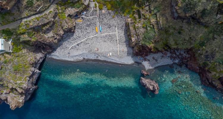 Aerial view of a rocky beach with clear blue water.