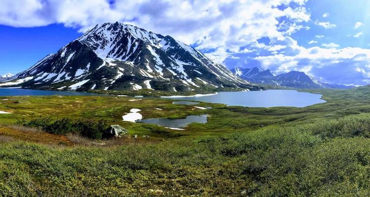 Landschappelijk uitzicht op een met sneeuw bedekte berg en meren in een weelderige vallei.