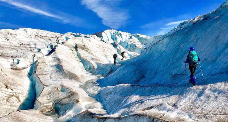Wandelaars die over een sneeuwbedekt gletsjerveld lopen.