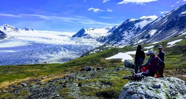 Group of people preparing for a hike with a glacier valley in the background.