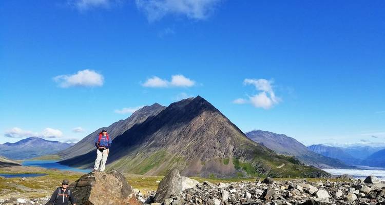 Persoon die staat op een rotsachtig pad met uitzicht op de bergen.