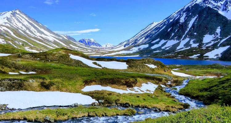 Prachtige vallei met stromend beekje en besneeuwde bergtoppen.