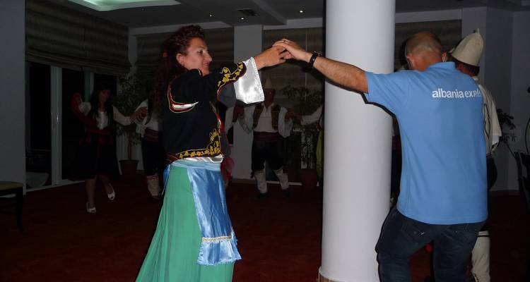 Mensen die binnenshuis dansen in traditionele klederdracht.