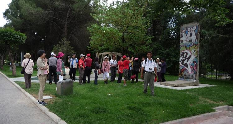 A group of tourists gathered around a piece of the Berlin Wall.