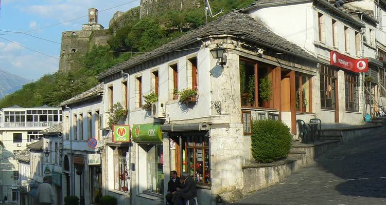 Stone buildings with a fortress in the background.