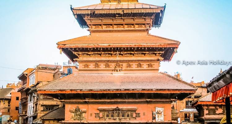 Grande structure de temple avec une toiture à étages dans une zone urbaine densément peuplée.