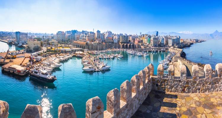 Panoramic view of Heraklion marina, cityscape and distant mountains from a historic fortress.