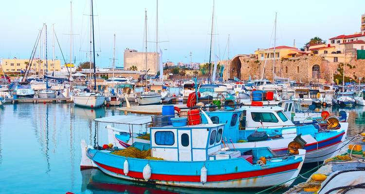 Colorful fishing boats moored in the tranquil Venetian harbor of Heraklion at dusk.