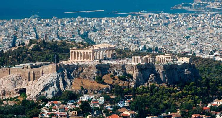 Breed stadspanorama van Athene met het Acropolis-plateau dat uitkijkt over dichte stedelijke bebouwing en de Egeïsche Zee.