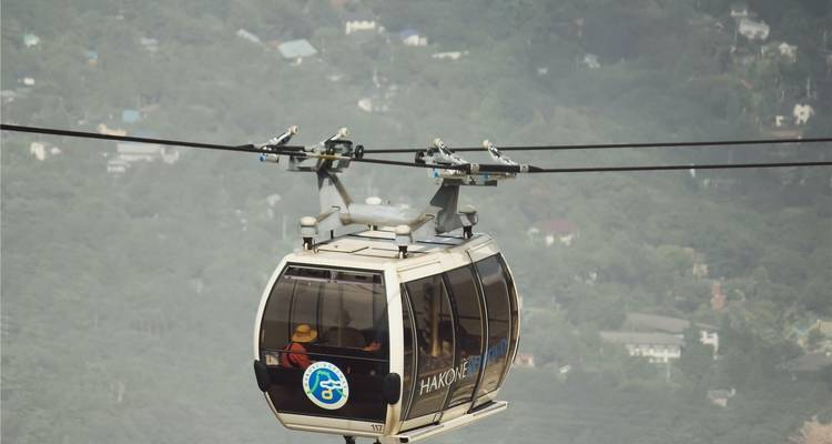 Una góndola del teleférico de Hakone se desliza sobre las laderas montañosas boscosas y brumosas.