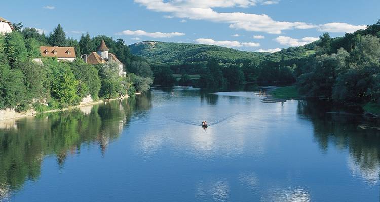 Une scène de rivière sereine avec un bateau et des forêts luxuriantes de part et d'autre.
