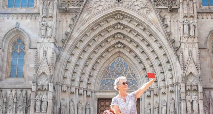 Personne en tenue grise prenant un selfie devant une cathédrale historique.