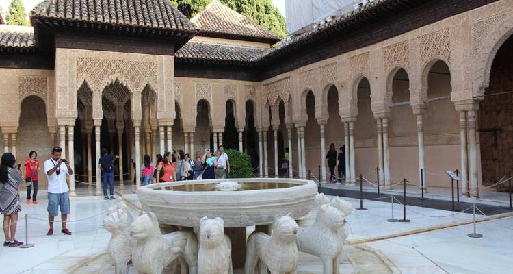 Des touristes autour d'une fontaine dans une cour historique.